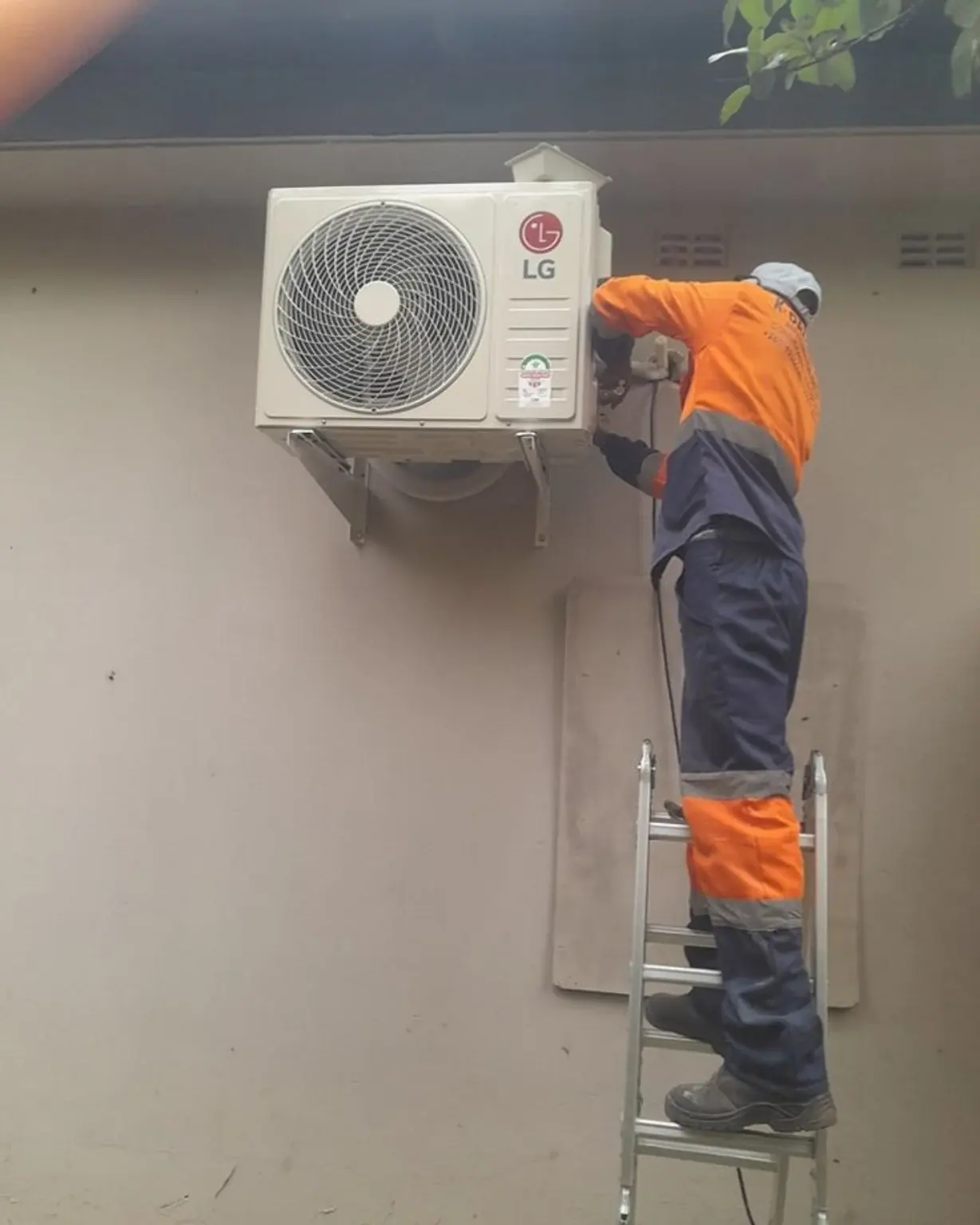 Technician attending to a wall-mounted outdoor air-conditioning unit